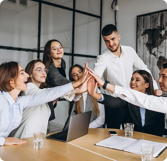 Team members in a meeting joyfully giving high fives, symbolizing collaboration and success.